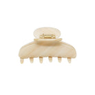 Cream-colored plastic hair claw clip with rounded top and six teeth, featuring gold-tone metal clasp mechanism