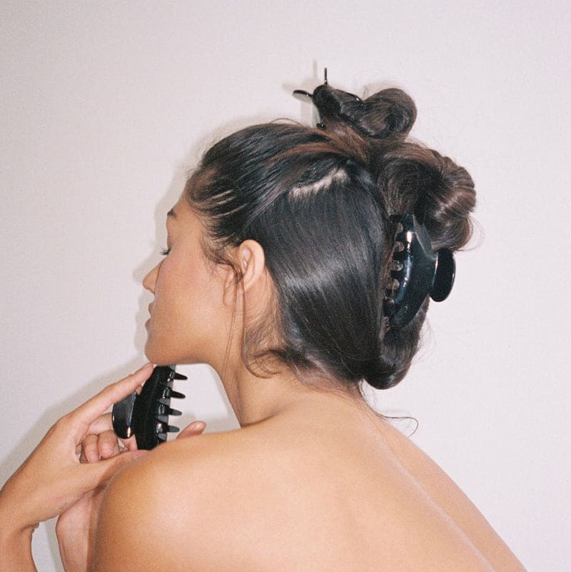 Large black claw hair clip securing an updo hairstyle, showing smooth glossy finish and secure grip on dark brown hair