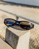 Black sunglasses on a concrete block with a blurred outdoor background