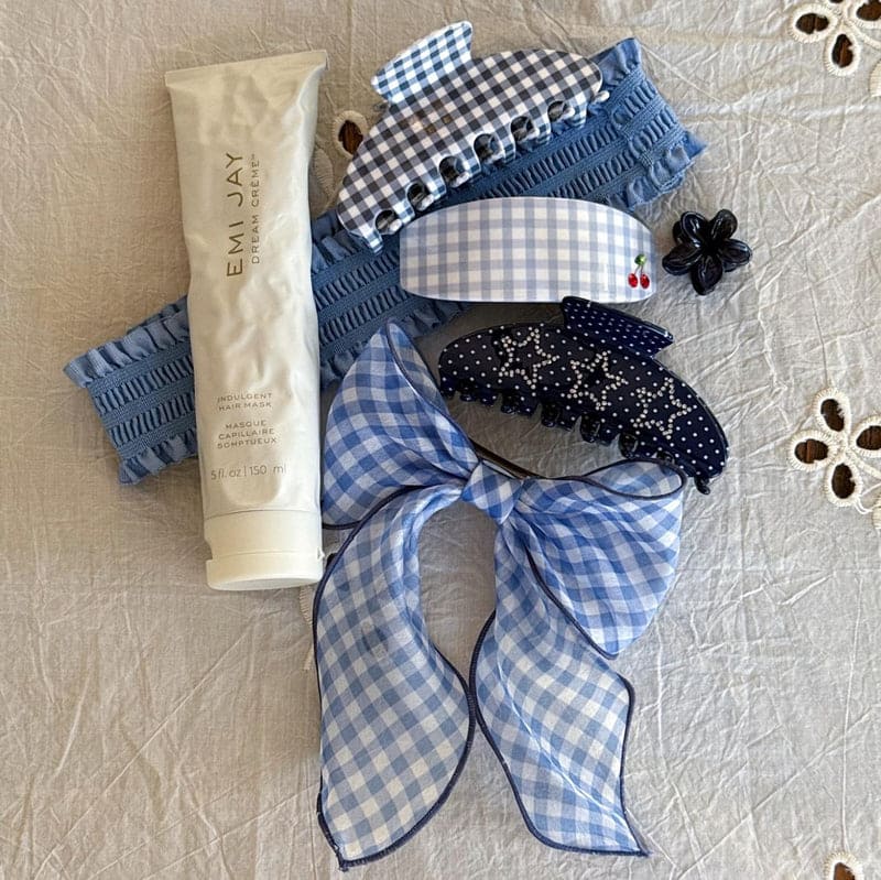 Blue gingham hair accessories set with knit headband, hair clips, scrunchies and bow on cream lace background with hand cream