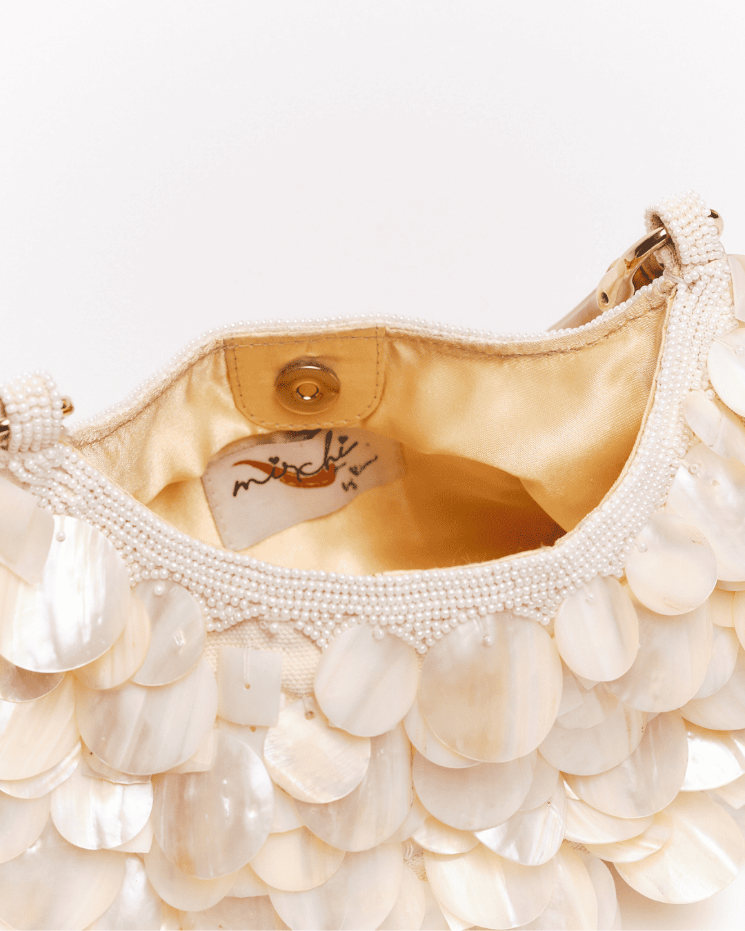 Cream beaded handbag with mother-of-pearl shell disc embellishments and gold satin lining, shown open with magnetic closure