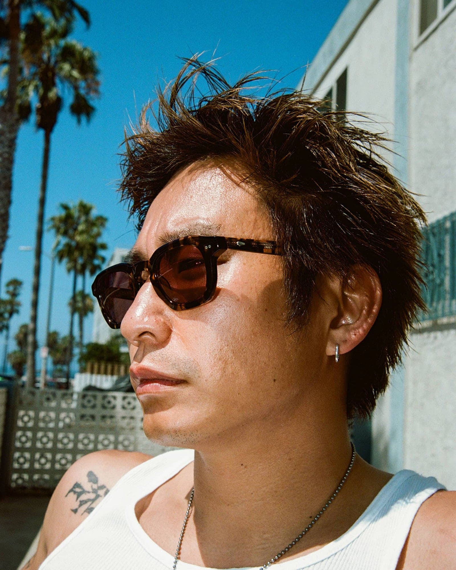 Person wearing black tortoiseshell sunglasses with brown gradient lenses outdoors in sunny California setting