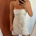 Person wearing a strapless lace dress taking a mirror selfie.