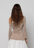 Taupe cold-shoulder long-sleeve top with flared cuffs, worn with a white tiered maxi skirt, back view.