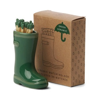 Green ceramic wellington boot match holder with matches next to cardboard packaging box