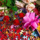 Colorful jigsaw puzzle pieces scattered among fresh roses in pink, red, and peach tones with green foliage