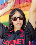 Person wearing sunglasses and a black shirt with red text in front of a colorful background