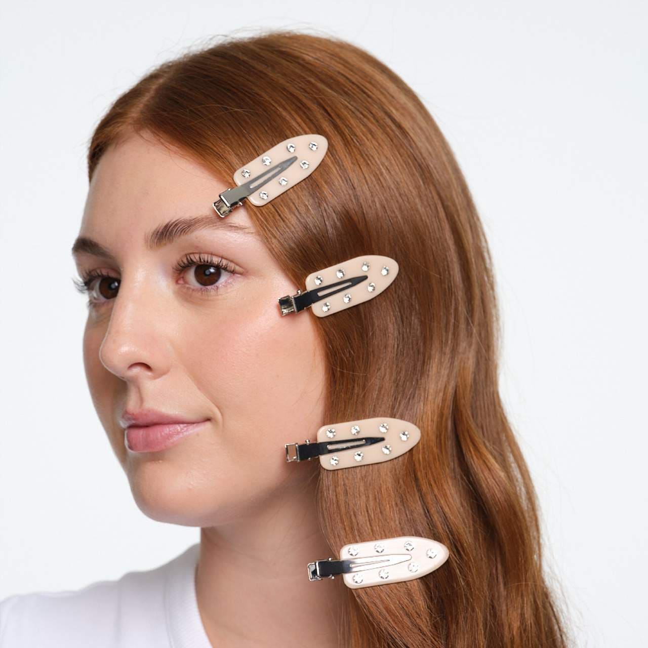 Woman with auburn hair wearing four pearlescent snap hair clips with silver studs arranged vertically down the side