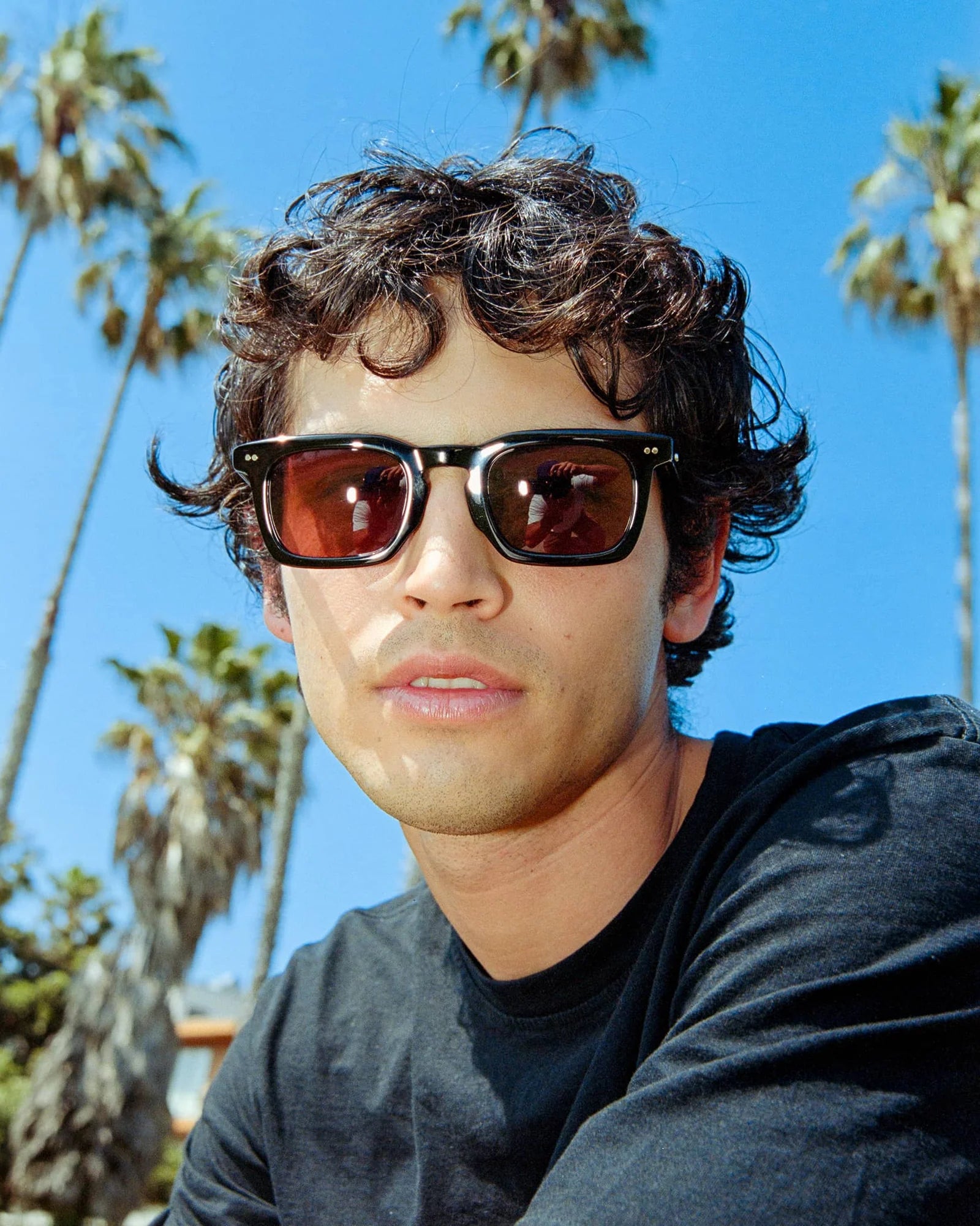Man wearing sunglasses with palm trees in the background