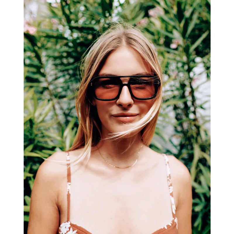 Woman wearing large sunglasses with a green leafy background