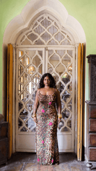 Woman in leopard print maxi dress with floral embroidery standing in ornate arched doorway with decorative white lattice doors