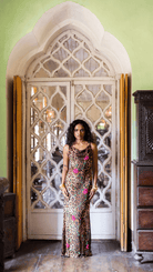 Woman in leopard print maxi dress with pink floral embroidery standing in ornate white archway doorway