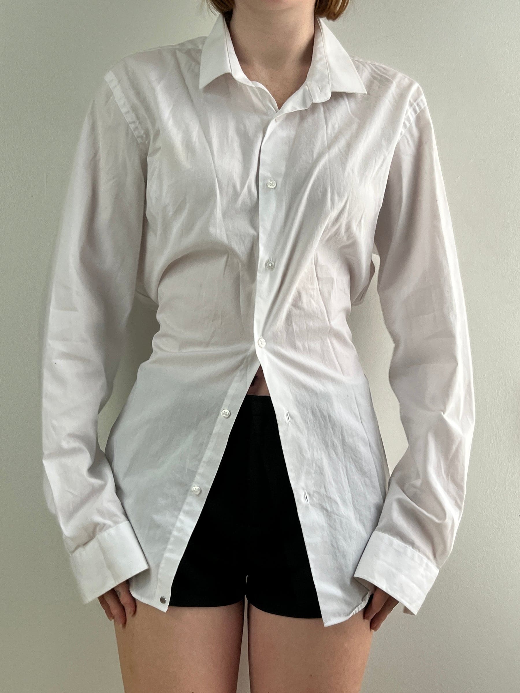White oversized button-up shirt with collar, paired with black shorts, featuring long sleeves and relaxed fit