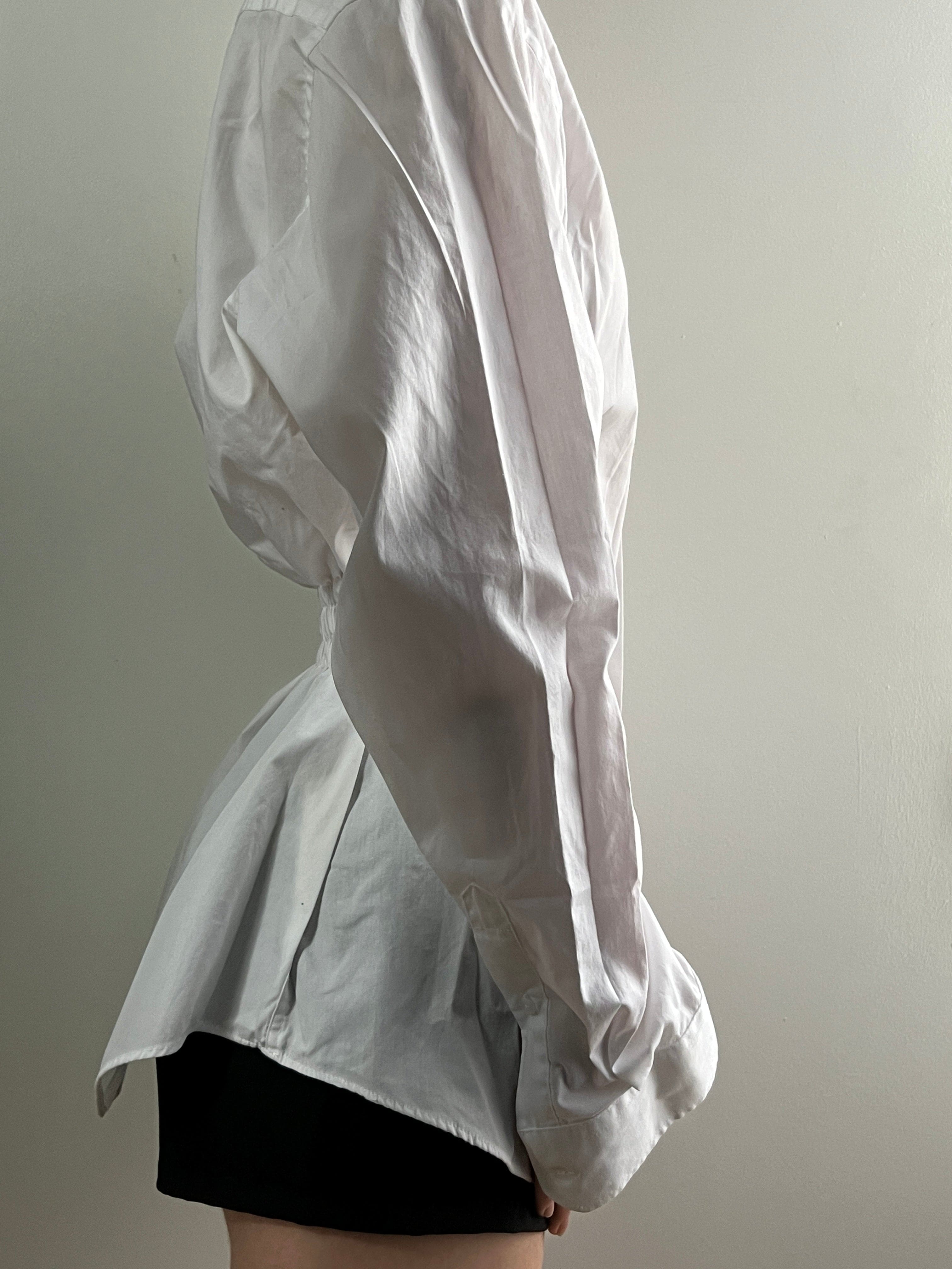 White oversized linen shirt with relaxed fit and rolled cuffs, worn with black shorts against neutral background