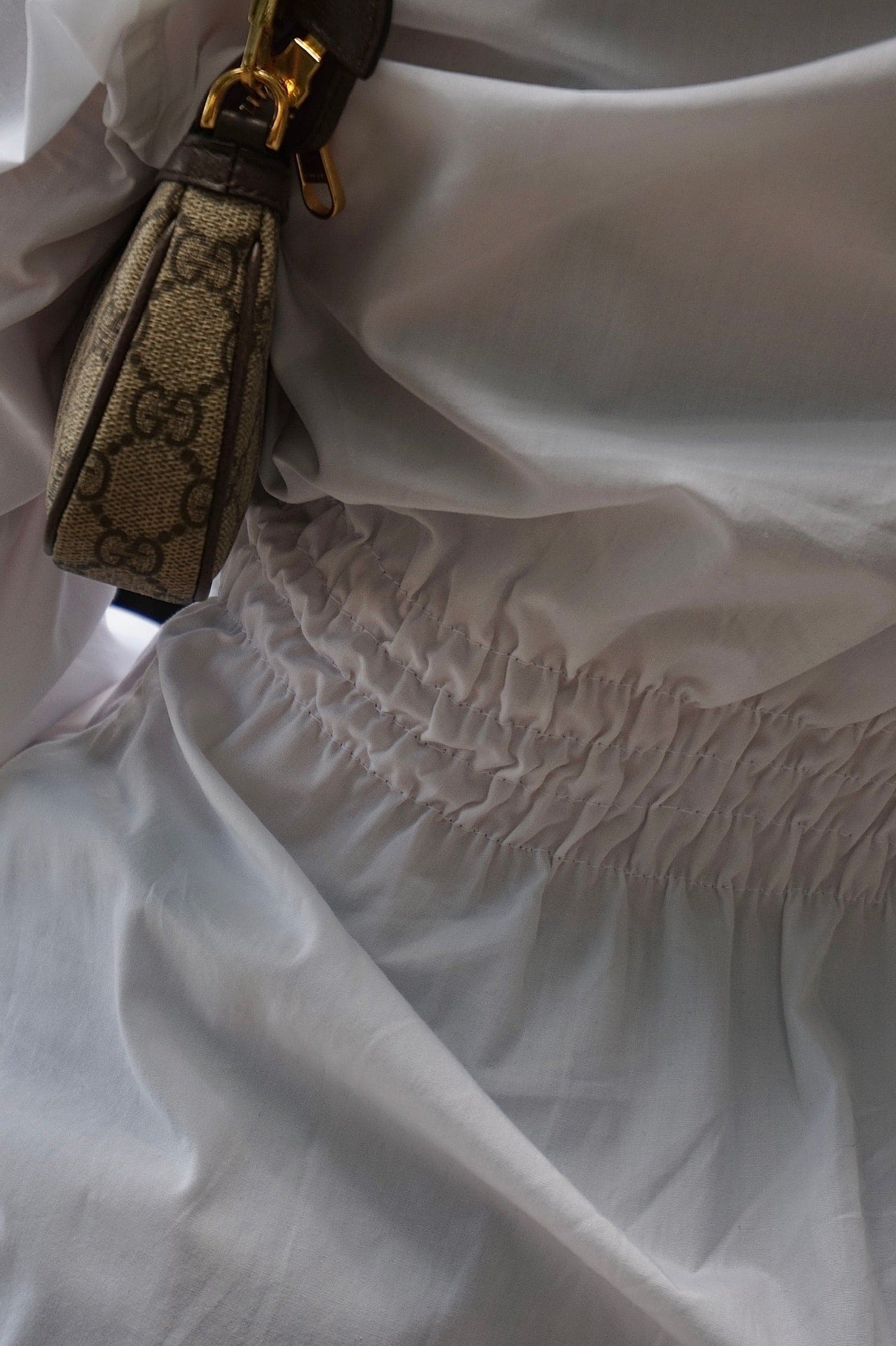 White gathered dress with beige Gucci monogram strap and gold hardware detail