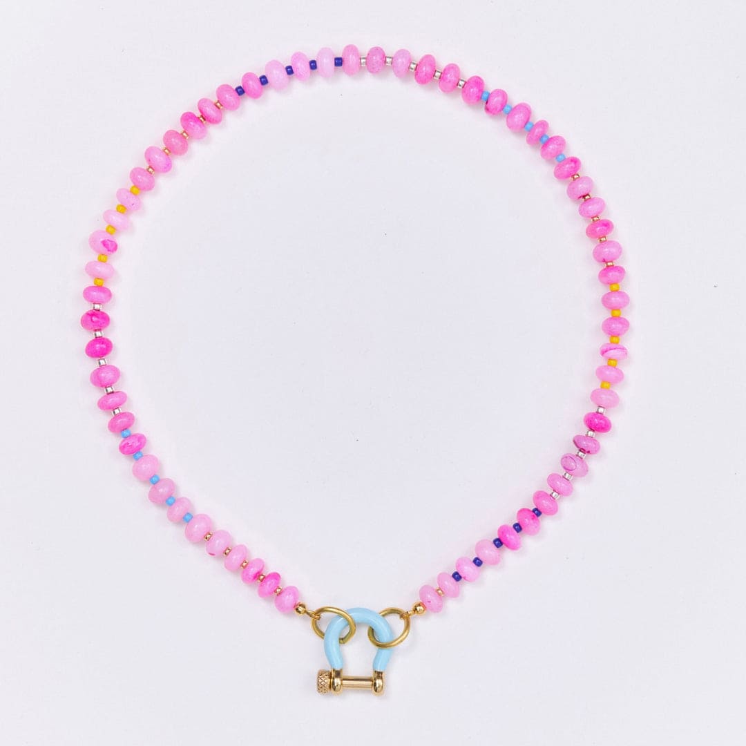 Pink beaded necklace with small metallic spacer beads and blue enamel toggle clasp on white background