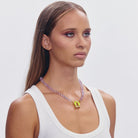 Pink beaded necklace with yellow butterfly pendant charm on white tank top model