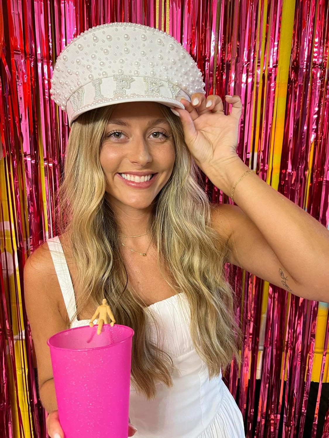 White pearl-studded wifey cap with rhinestone lettering and dome-shaped crown, worn against pink metallic streamers