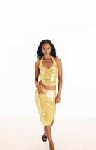 Yellow sequined two-piece set with halter crop top and midi skirt featuring shimmering embellishments