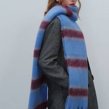 Blue and burgundy striped oversized fuzzy mohair scarf draped over gray wool coat, soft textured finish