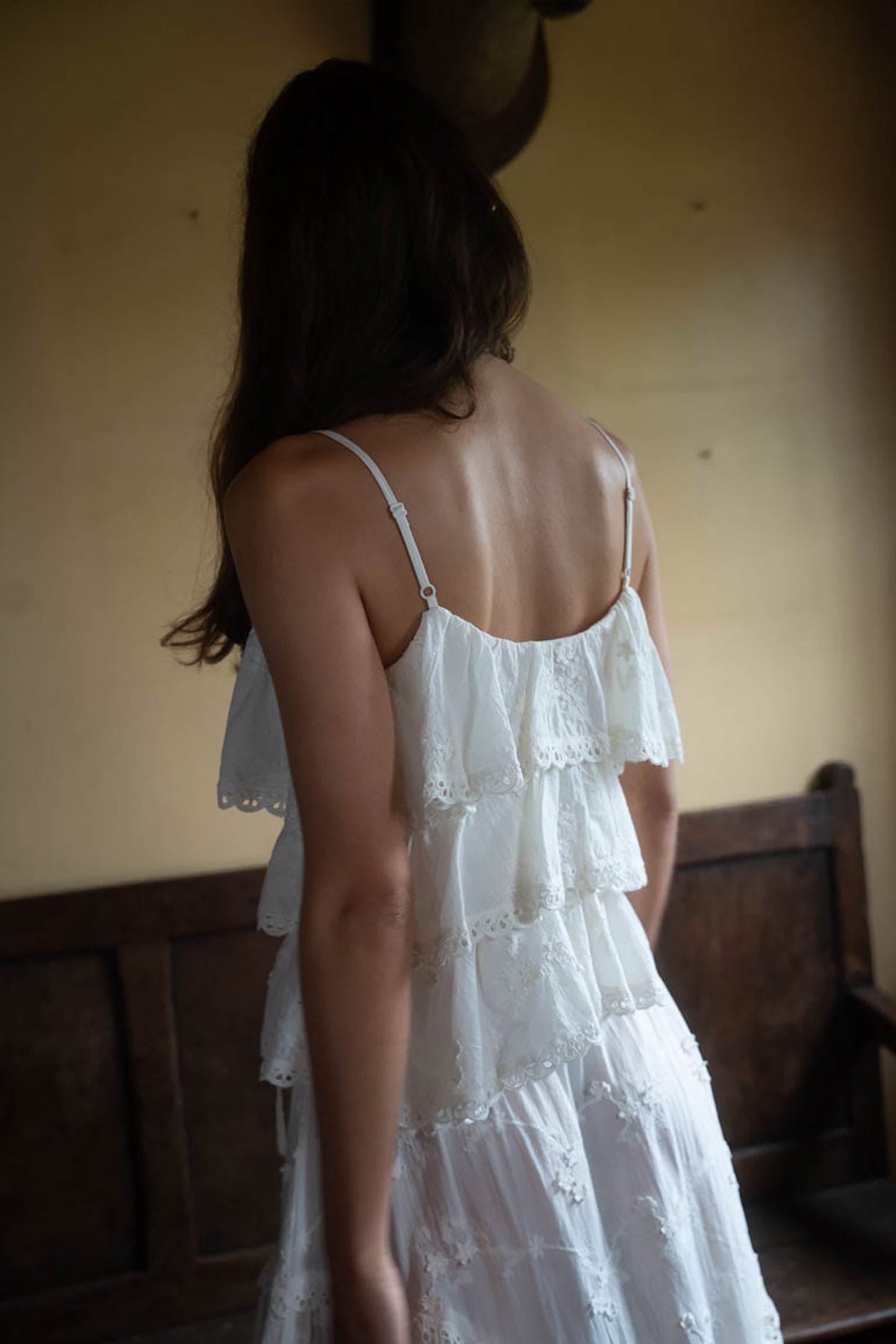 White tiered lace ruffle dress with adjustable spaghetti straps and eyelet trim detail, shown from back view