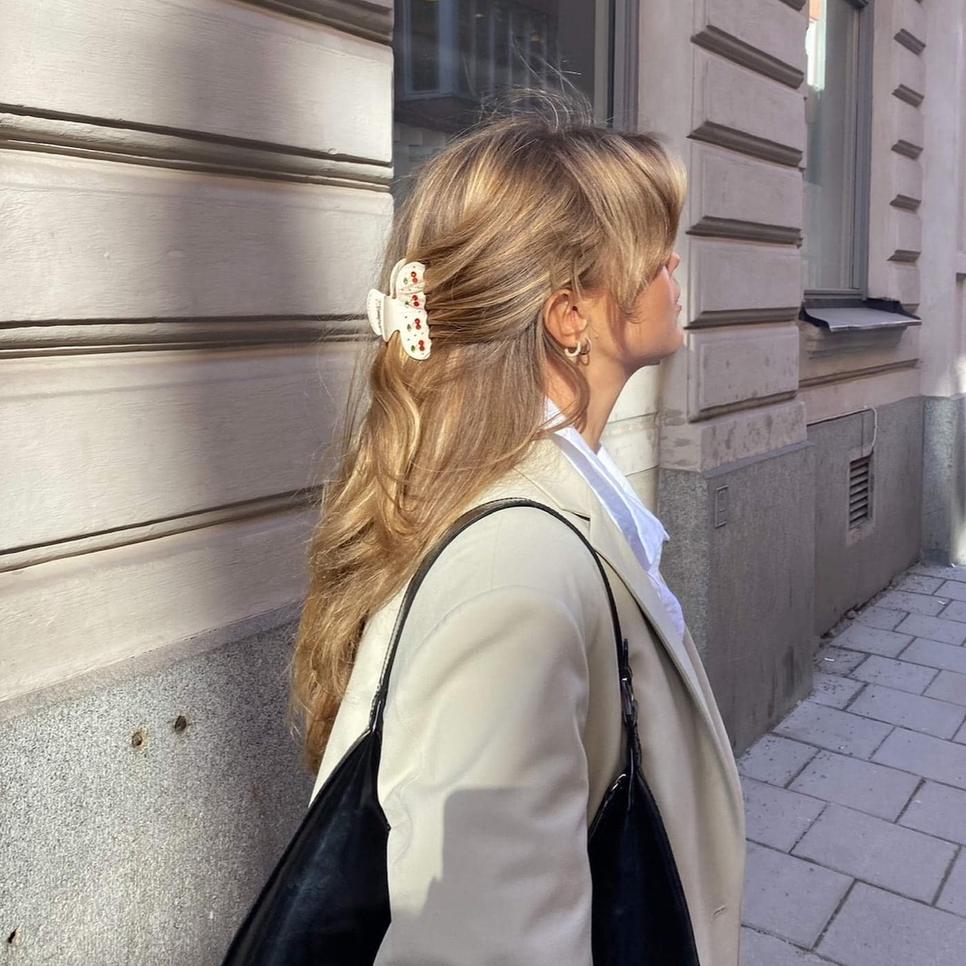 Cream-colored butterfly hair claw clip with red crystal embellishments worn in blonde hair, shown from side profile