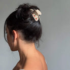 White ceramic bunny hair claw clip with red dot details securing dark hair in a messy bun updo