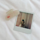Translucent white butterfly hair claw clip with pink and clear crystal embellishments on white fabric background