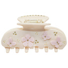 Beige hair claw clip with pink flower embellishments and gold rhinestone accents on a white background
