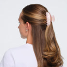 Pink marbled hair claw clip with gold hardware securing half-up hairstyle on brunette hair