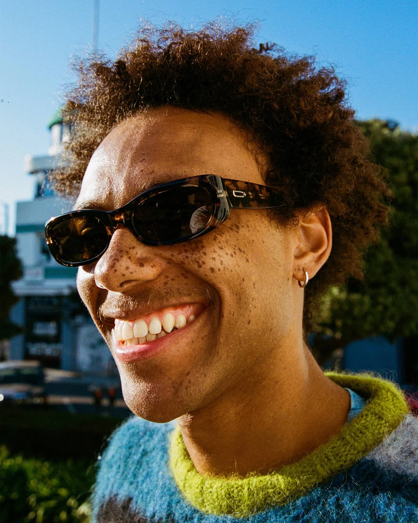 Person wearing sunglasses and a colorful sweater with a blurred background