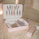 Pink travel case organizing beauty tools and skincare products with clear compartments and elastic straps on bathroom counter